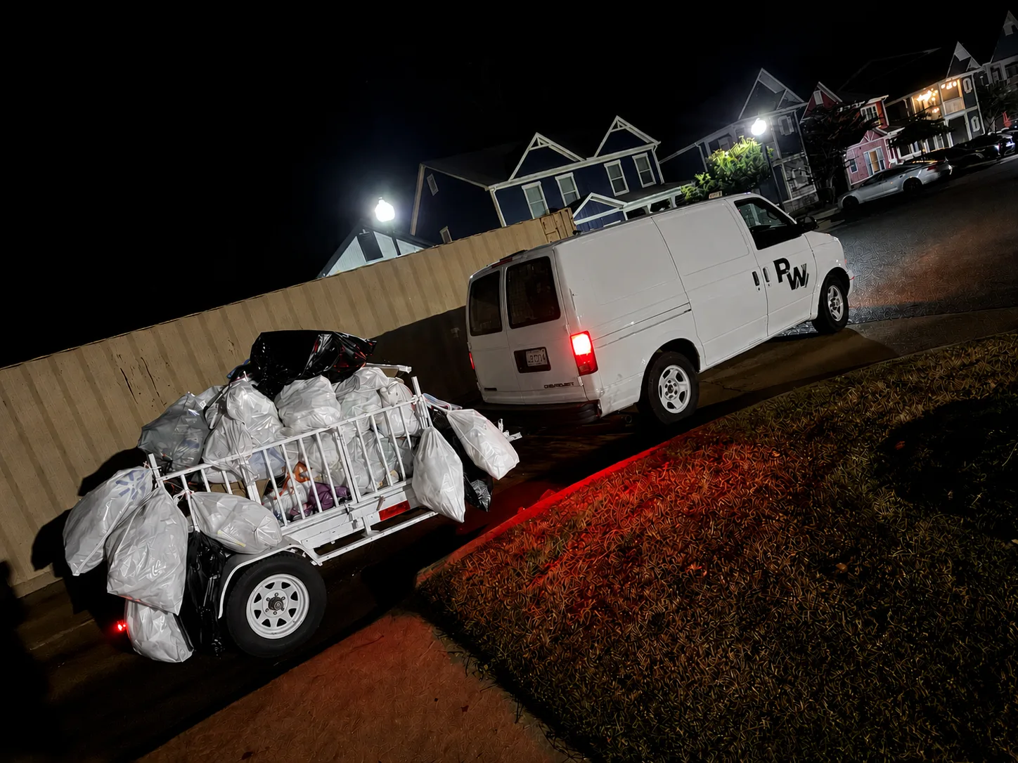 Premium Waste van and collection trailer loaded with bagged trash during evening service at an apartment community